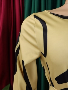 Detail view of yellow long-sleeved dress with black abstract geometric patterns