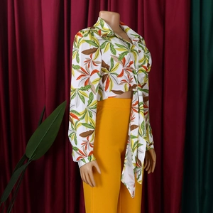 Detail of white tropical leaf print blouse with front tie and vibrant yellow pants