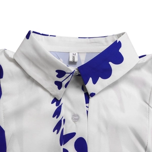 Detail of printed shirt collar with white buttons and blue leaf pattern on white fabric