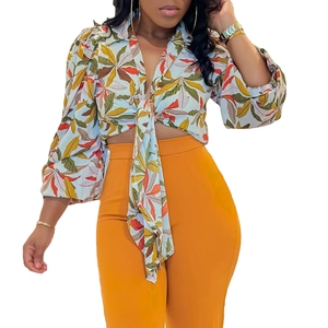 Detail of floral print crop top with tie-front design and bright orange high waist trousers