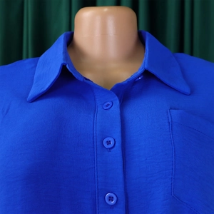 Detail of royal blue short sleeve shirt with lapel collar, buttons and chest pocket