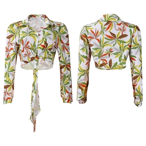 Detail of tropical print blouse showing lapel collar, button front, and front tie hem design