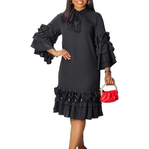 Close-up of bow tie neckline and layered ruffle cuffs with white pearl embellishments