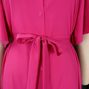 Detail of rose pink dress featuring a single-breasted button front and a waist tie bow