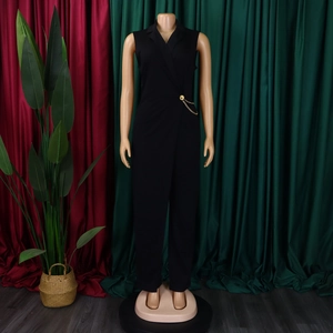 Detail of a black sleeveless jumpsuit featuring a chic notch lapel and gold waist chain