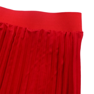 Detailed view of red pleated skirt showing the elastic waistband and fabric texture