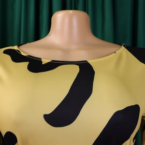 Gros plan sur l'encolure de la robe jaune avec motifs noirs et texture de tissu premium