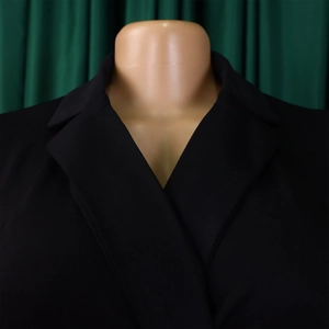 Detail shot of a black sleeveless notched lapel neckline on a solid jumpsuit