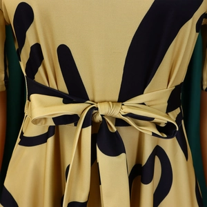 Détail d'une robe jaune gingembre avec des taches noires et une ceinture à nouer