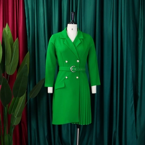 Detail of green blazer dress with double-breasted buttons and pleated asymmetric skirt