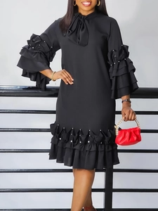 Elegant black long sleeve dress with layered ruffle sleeves and white pearl trim details