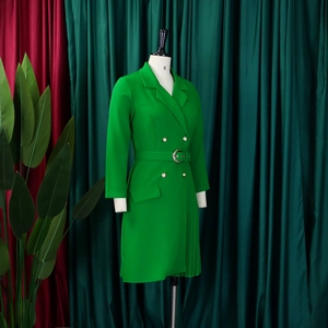 Detail of waist belt with round buckle and pleated hem on a green blazer dress