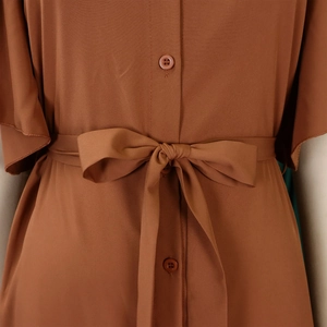 Detail of caramel brown dress featuring a waist tie bow and resin buttons