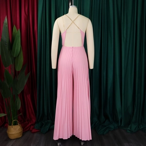Detail view of pink pleated jumpsuit featuring backless design and gold chain straps
