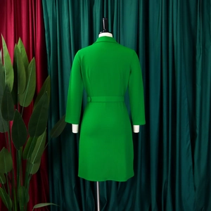 Detail of the back of a bright green long sleeve midi dress with matching slim waist belt