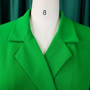 Detail of classic notch lapel and textured woven fabric on bright green blazer dress