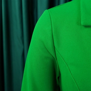 Detailed macro view of the lapel and shoulder stitching on a bright green blazer dress