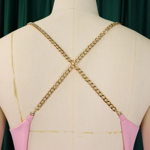Detail of pink backless jumpsuit featuring gold metal chain straps and cross-back design