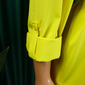Detail of roll-up cuff with button tab on a bright yellow cotton shirt dress sleeve