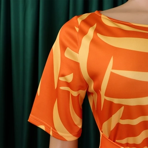 Détail de robe africaine orange avec motifs de feuilles jaunes et encolure ronde élégante