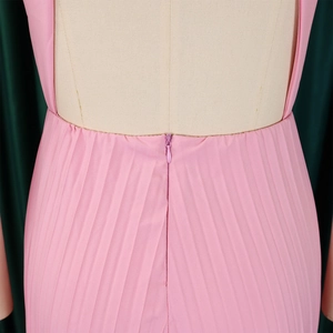 Detailed view of pink pleated jumpsuit featuring a back invisible zipper and fine texture