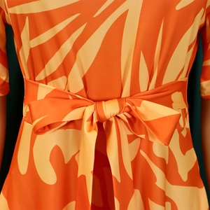 Détail du nœud à la taille sur une robe à imprimé abstrait orange et coupe ajustée