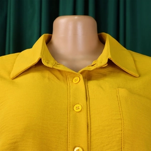 Detail of bright yellow casual shirt featuring classic lapel collar and button-down front