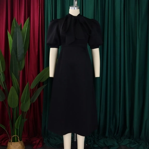 Detail of elegant black retro dress with puff sleeves and bow tie on a velvet background