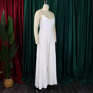 Detail of white pleated jumpsuit featuring a gold metal chain halter neck and cowl neckline
