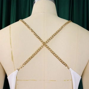 Detail of elegant back design with crisscross gold metal chains on a white wide-leg jumpsuit