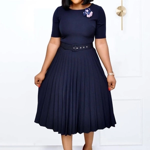 Detail of navy blue pleated dress with round neck, short sleeves and floral brooch detail
