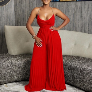 Detail of red pleated jumpsuit featuring elegant gold chain straps and a deep V-neckline