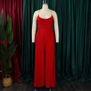 Detailed view of red pleated wide-leg jumpsuit with gold chain straps and draped neckline