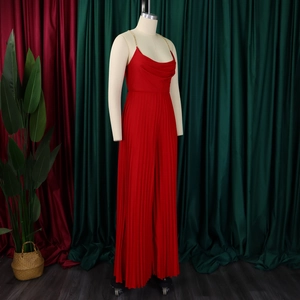 Detail of red pleated jumpsuit with elegant gold chain halter neckline and high waist
