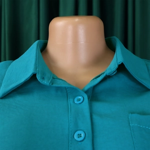 Detail of the peacock blue shirt collar with matching resin buttons and pocket stitching