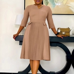Close-up of pleated details and decorative pocket flaps on solid tan midi dress