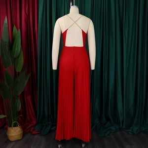 Detail of red pleated jumpsuit featuring a backless design with gold chain cross straps