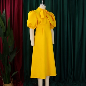 Detail of the bright yellow puff sleeve dress with a large bow tie on the neckline