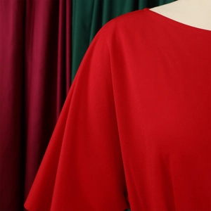 Close-up of red wide-leg jumpsuit showing shoulder detail and ribbed fabric texture