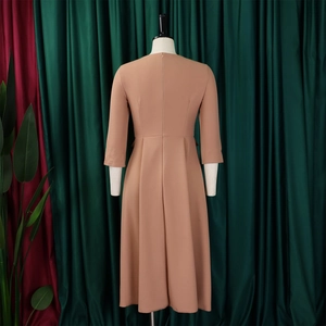 Detail view of the camel midi dress with elegant pleated skirt and three-quarter sleeves