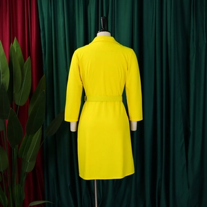 Detail of a bright yellow midi dress featuring a tailored blazer collar and matching fabric belt