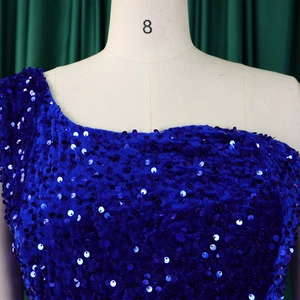 Detailed macro view of royal blue sequins and velvet fabric on a one-shoulder gown