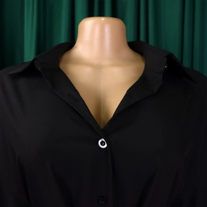 Detail of a black button-up shirt featuring a classic lapel collar on a mannequin