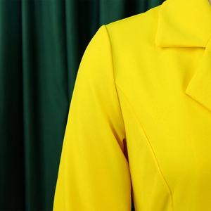 Close-up of bright yellow blazer details including structured shoulders and notch lapels