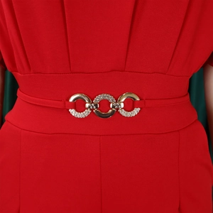 Detail of red knit jumpsuit waist with golden buckle and sparkling rhinestones