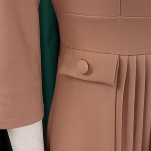 Close-up of pleated skirt detail in mocha brown with decorative pocket and fabric button
