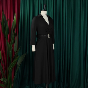Detail des eleganten schwarzen Langarmkleides mit Taillengürtel und Metallschnalle