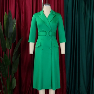 Détail d'une robe croisée vert vif avec ceinture et poches à rabat sur un mannequin de couture