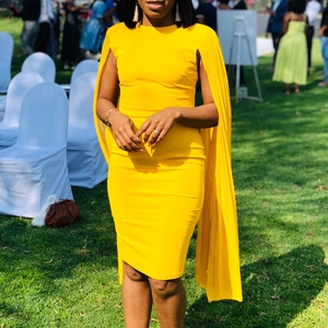 Detail of bright yellow dress featuring elegant pleated cape sleeves and a slim fit cut