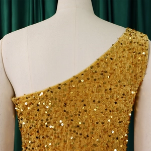 Detail of elegant one shoulder evening dress with golden sequins and pleated fabric
